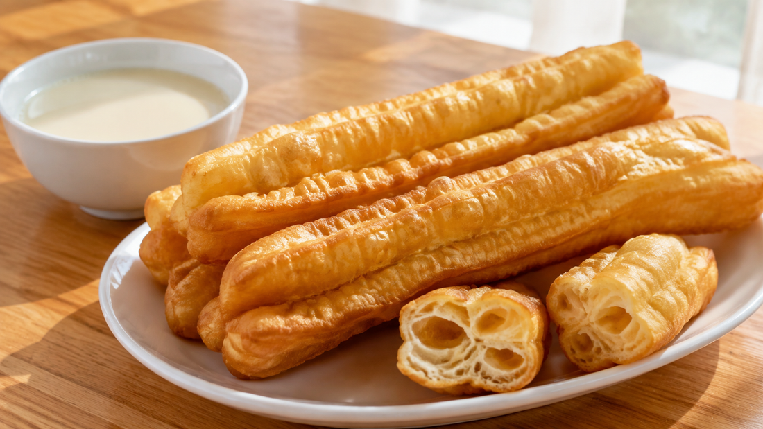 Golden Chinese youtiao fried dough sticks with airy interiors beside a bowl of warm soy milk