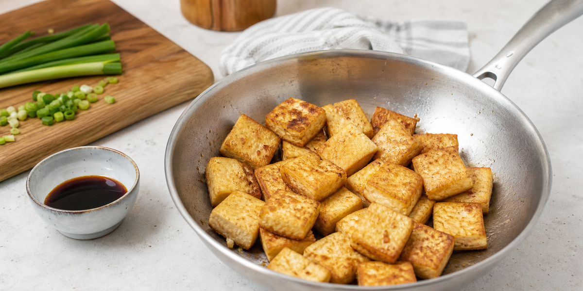 Golden Chinese-style crispy tofu cubes in a stainless-steel skillet