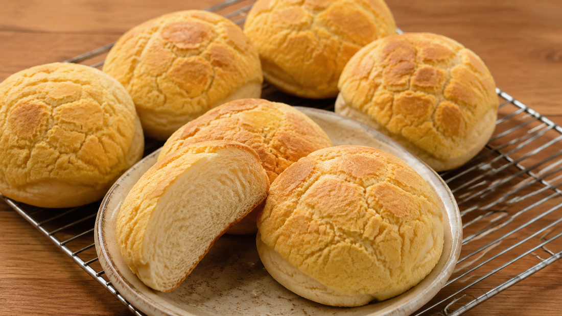 Hong Kong pineapple buns with golden cracked cookie crust and one cut open to show fluffy bread
